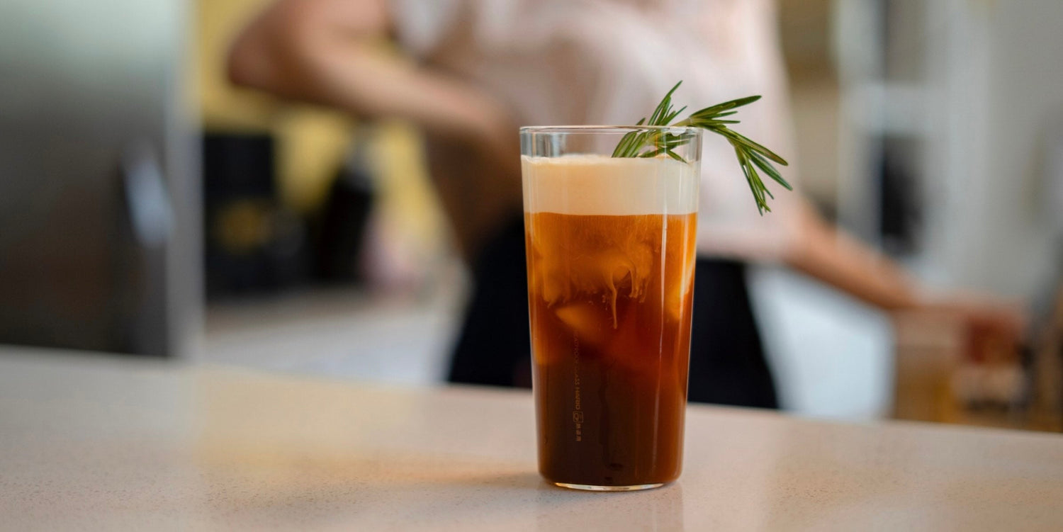 cold brew coffee with vanilla cold foam and rosemary garnish