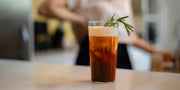 cold brew coffee with vanilla cold foam and rosemary garnish